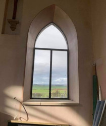 An image of a medieval church style window with fresh plastering done around it